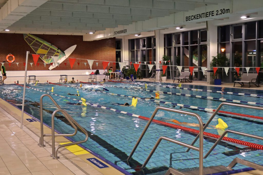 Schwimmtrainingsbild, mehrere Schwimmer auf mehrere Bahnen schwimmen auf dem Rücken und halten Bretter in den Händen.